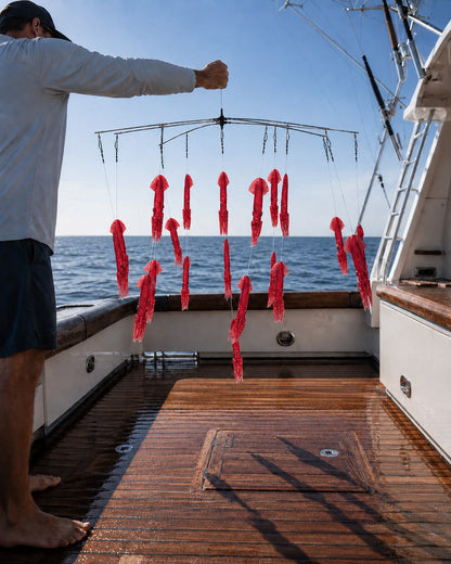 Compact Squid Dredge in red held over the gunwale offshore | Epic Fishing Co.